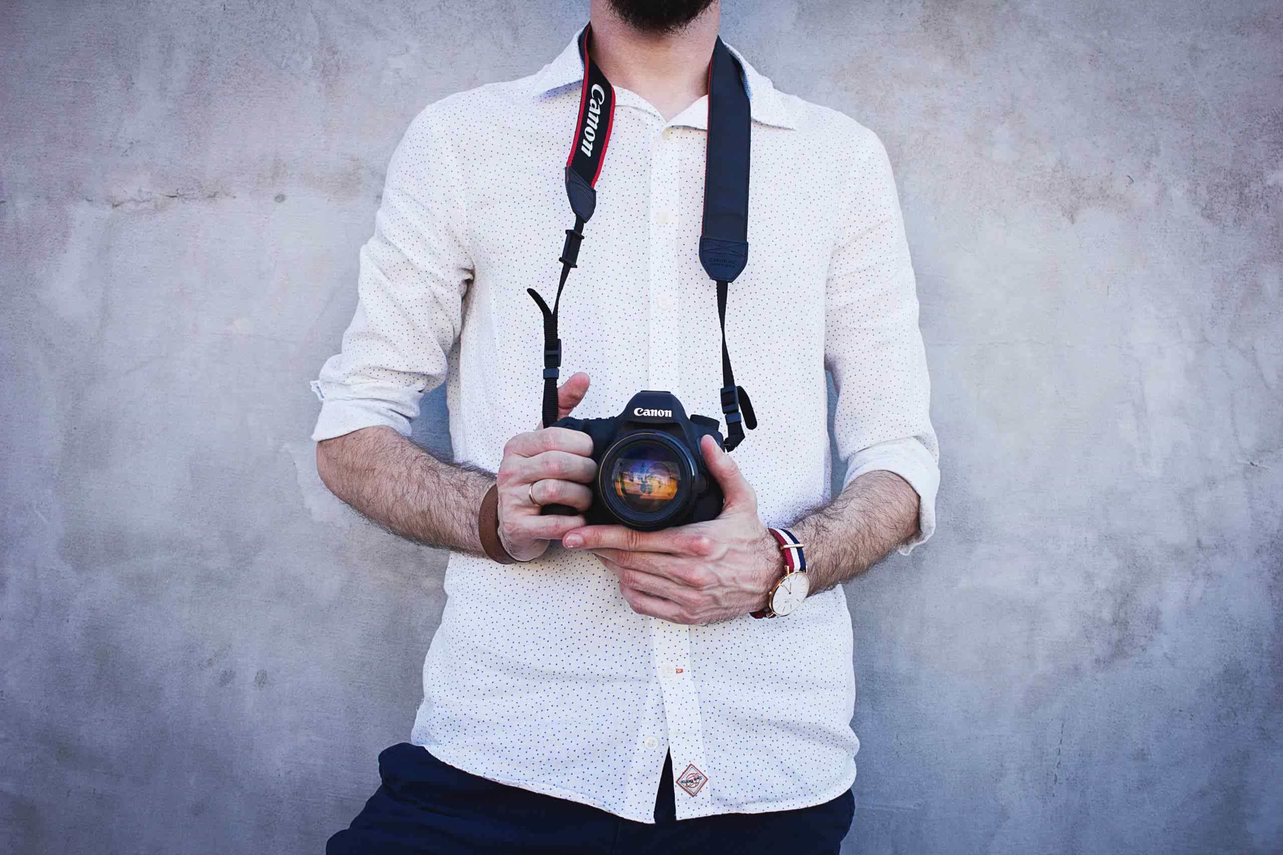 a photographer in a white shirt by a wall